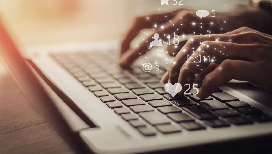 Notebook em uso com ícones de redes sociais sobrepostos